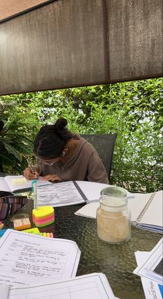 a woman sitting at a table writing on paper