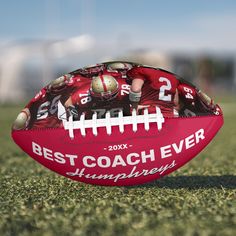 a football sitting on top of a field with the best coach ever written on it