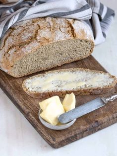 a loaf of bread sitting on top of a cutting board next to butter and a knife