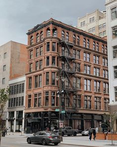 a fire escape on the side of a building in an urban area with cars parked nearby