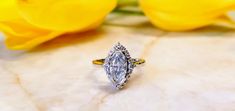 a diamond ring sitting on top of a white marble surface next to yellow flowers and tulips