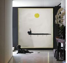 a black dog laying on the floor in front of a painting with a yellow sun above it