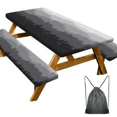 a picnic table with two benches and a drawstring bag on the ground next to it