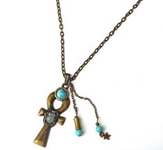 "A mystical necklace featuring a large Egyptian ankh pendant with a scarab beetle decoration, an ancient symbol of the resurrection of life, accented with painted touches of lustrous violet and turquoise! A little violet Swarovski crystal rhinestone sparkles from its back and turquoise blue magnesite beads dangle alongside the unique pendant! A faux turquoise stone sits at the top of the ankh pendant as yet another design element. The luck-bringing pendant dangles from a sturdy antiqued gold cha Scarab Pendant, Mystical Necklace, Ankh Pendant, Egyptian Ankh, Scarab Beetle, Large Necklace, Egyptian Jewelry, Bohemian Accessories, Allegiant