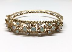 "Estate 14k Yellow Gold Filigree W/ Rope Edge Detail Opal & Diamond Hinged Bangle Bracelet Material: 14k yellow gold, stamped Weight: 22.9 grams Size: Top is 12mm wide tapering to 10.50mm on sides and 5mm on bottom, Bracelet is 2.50mm in diameter, 2 1/2\" attached safety chain Stones: 7 round fiery opals 3.70 - 4mm each 8 round fiery opals 2.50 - 2.60mm each 4 round cut diamonds 2.50 - 2.60mm each, SI2 - I1 clarity, G - H color Hallmarked: 14k Side hinge opening with a safety figure 8 Side h Ornate Yellow Gold Bracelets For Formal Occasions, Ornate Yellow Gold Bracelet For Formal Occasions, Yellow Gold Filigree Bracelet For Formal Occasions, Heirloom Yellow Gold Bracelet With Filigree, Heirloom Yellow Gold Filigree Bracelet, Antique Yellow Gold Bracelet For Evening Wear, Antique Yellow Gold Bracelets For Evening, Formal 14k Gold Filigree Bracelets, Ornate Hallmarked Yellow Gold Bracelet