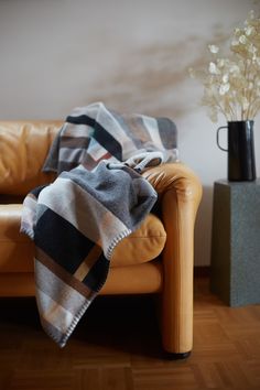 a couch with a blanket on top of it next to a vase filled with flowers