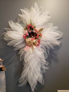 a white wreath hanging on the wall next to a vase