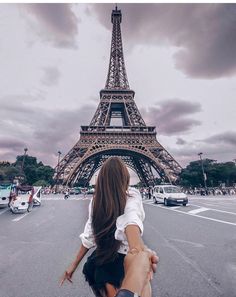 a woman taking a selfie in front of the eiffel tower