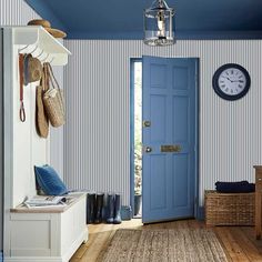 a blue door in a room with striped walls and wooden flooring next to a bench