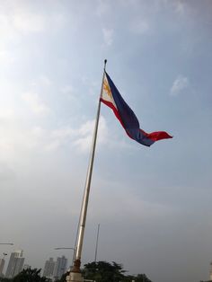 the flag is flying high in the blue sky with tall buildings in the back ground