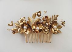 two gold hair combs with flowers and leaves on them, sitting side by side