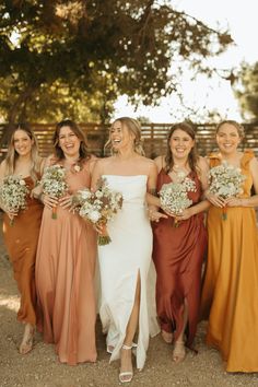 a group of women standing next to each other wearing dresses and holding bouquets in their hands