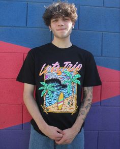 a young man standing in front of a blue and red wall wearing a black shirt