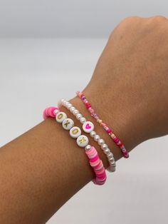 a woman's arm wearing three bracelets with beads and letters on them,