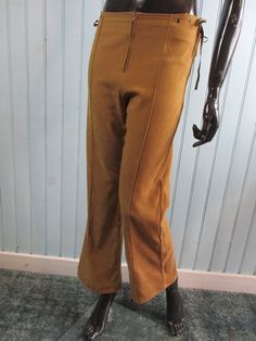 Retro 70s trouser in tan faux moleskin. Flat waist flares with a front zip and brown laces at the sides, boot cut. Dimensions: Waist: 30 Inches. Hip: 38 Inches. Inside leg: 29 Inches Made in France Vintage Trousers For Winter, Vintage Winter Trousers, Vintage High Waist Winter Pants, Vintage Wide Leg Pants For Winter, Retro Winter Trousers, Vintage Cargo Pants For Fall, 70s Inspired Fitted Pants For Fall, Vintage Fall Pants With Pockets, 70s Inspired Fitted Fall Pants