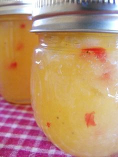 two jars filled with food sitting on top of a checkered tablecloth covered table