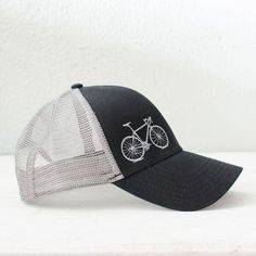 Stay stylish with our Monochrome Vital Bike Baseball Hat, featuring a sleek gray design with matching mesh back. The understated embroidered bike logo adds a cool, minimalist touch, perfect for those who prefer a low-profile look. Crafted from a blend of cotton, nylon, and polyester, this hat offers comfort and durability. With an adjustable snapback closure, it ensures a perfect fit for most. Imported cap, expertly embroidered in the USA. Ideal for casual outings and everyday wear. Black color Made in Wisconsin Custom Corporate Gifts, Trucker Hat Black, Bike Logo, Gifts For Hubby, Women Embroidery, Gift Catalog, Embroidery Baseball, I Want To Ride My Bicycle, Cap Men