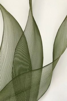 an abstract sculpture is shown against a white wall and has wavy lines in the shape of leaves