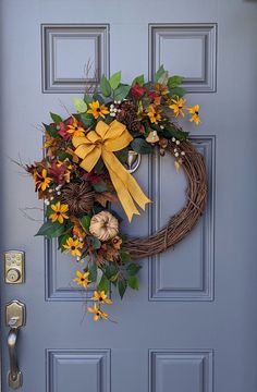 a wreath on the front door with yellow flowers and leaves hanging from it's side