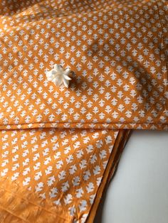 an orange and white patterned cloth with a flower on the end, sitting on a table