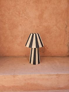 a black and white striped lamp sitting on top of a step next to a wall