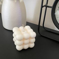 a white vase sitting on top of a table next to a clock