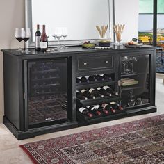 a black buffet with wine bottles and glasses on it in front of a large mirror