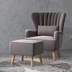 a chair and footstool sitting on a rug in front of a gray wall