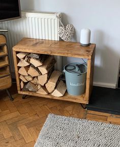 a pile of wood sitting on top of a wooden floor next to a metal trash can