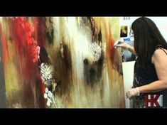 a woman is painting on an easel in front of a large piece of art