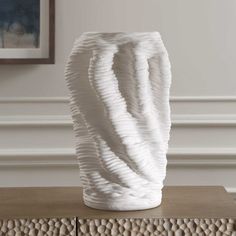 a white vase sitting on top of a wooden table