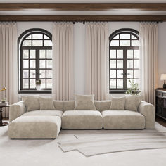 a living room with two large windows and a sectional couch