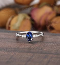 an oval shaped blue sapphire and diamond ring on a table with yarns in the background