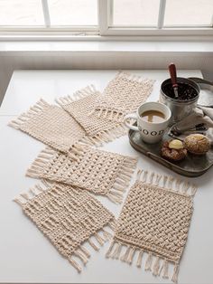 crocheted placemats on a table with coffee and doughnuts next to them