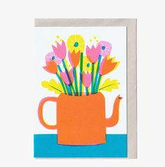 an orange watering can with flowers in it