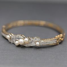 This stunning bracelet is a perfect period piece in exquisite condition. The bracelet features a bangle design with a hinged opening at the side. The top of the bracelet is encrusted with diamonds and pearls. The pearls and cultured and measure 6.14mm (largest and 3.84 (smallest). The design features single cut round diamonds, thirty two of them. The stones are VS/SI clarity and are G/H color. They measure 1.5mm each for a total weight of 0.48cttw. The piece is constructed in solid 14k yellow go Formal Diamond Oyster Bracelet, Classic Diamond Bracelet With Oyster Style For Wedding, Classic Diamond Oyster Bracelet For Wedding, Elegant Pearl Bracelet With Diamond Accents, Formal Diamond Pearl Bracelet With Jubilee Style, Formal Diamond Bangle Bracelet With Oyster Detail, Exquisite Bangle Diamond Bracelet With 17 Jewels, Exquisite Diamond Bangle Bracelet With 17 Jewels, Heirloom Diamond Bracelet With Diamond Accents For Wedding