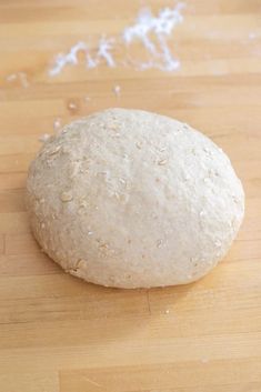 a ball of bread sitting on top of a wooden table next to a pile of flour