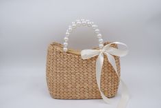 a straw bag with a white ribbon and pearls