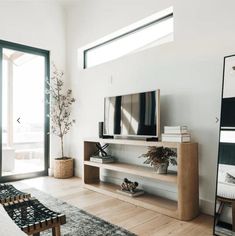 a living room with white walls and wood flooring has a large tv on the wall