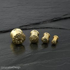 three gold ear plugs sitting on top of a black stone floor next to each other