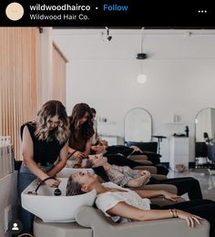 three women are getting their hair done in a salon while another woman sits on the floor