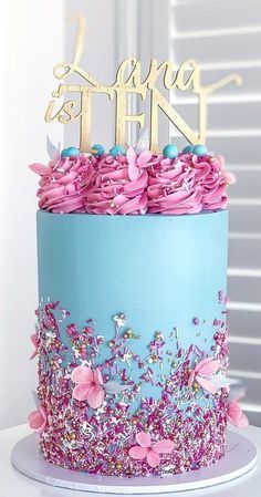 a blue and pink cake with flowers on top