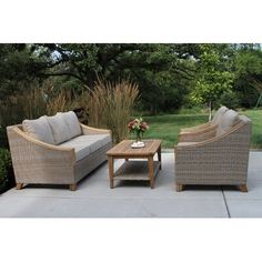 an outdoor living room with wicker furniture and flowers on the table in front of it