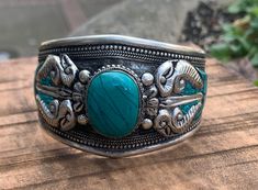 Vajra or Dorje Cuff bracelet. This is a beautiful Tibetan inspire Tribal Cuff with Vajra and Turquoise in the middle. Turquoise stone in the middle is carefully nested in the metal strip and also has inlaid turquoise around the cuff with intricate hand work. Made with a beautiful old time vintage appeal to it. Casual and cool piece to match with any outfit. Completely adjustable to any adult wrist size and is very comfortable to wear. Perfect for Male or Female. Size: 2.75" X 1.60" Adjustable Turquoise Cuff Bangle, Handmade Turquoise Spiritual Bangle, Handmade Spiritual Turquoise Bangle, Unique Turquoise Nickel-free Cuff Bracelet, Unique Nickel-free Turquoise Cuff Bracelet, Bohemian Turquoise Nickel-free Cuff Bracelet, Adjustable Turquoise Bangle For Festivals, Turquoise Bangle Bracelet For Festival, Bohemian Turquoise Bangle For Festivals