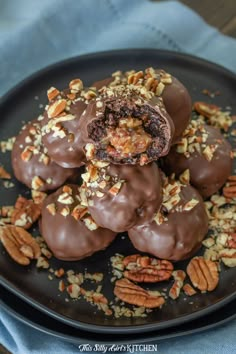 chocolate covered candies with pecans and nuts on a black plate, ready to be eaten