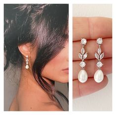 a woman's hand is holding two earrings and the other has a pearl drop