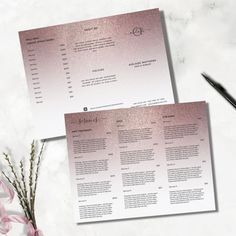 two pink menus sitting on top of a table next to a pen and flower