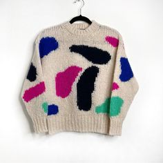 a white sweater with multicolored shapes on it