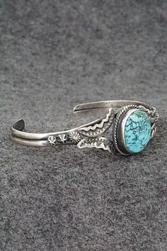 This beautiful natural Kingman turquoise and sterling silver bracelet was made by Navajo silversmith Gilbert Tom. The back is signed Gilbert Tom and stamped sterling.Size: 5 1/2" (will fit up to a 6 1/2" wrist)Gap: 1"Width: 3/4"Cuff Width: 1/4"Free shipping on all orders! We ship with USPS and always include tracking. All orders ship within a day of payment.Returns are accepted up to 30 days after you receive your order. Just send us a message. Our shop offers cash back or store credit. The item must be returned in new condition. Vintage Handmade Turquoise Sterling Silver Bracelet, Handmade Vintage Turquoise Sterling Silver Bracelet, Handmade Western Turquoise Bracelets, Handmade Western Turquoise Bracelet, Stamped Turquoise Bracelet, Handmade Western Style Turquoise Bracelet, Engraved Turquoise Jewelry Bracelet, Turquoise Stamped Bracelet, Engraved Turquoise Bracelet Jewelry