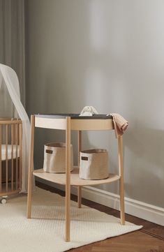 a baby crib in the corner of a room next to a table with two baskets on it